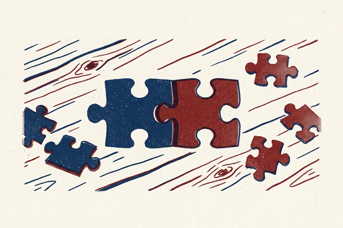 Two jigsaw pieces of different colours fitting together on a table, with loose pieces nearby.