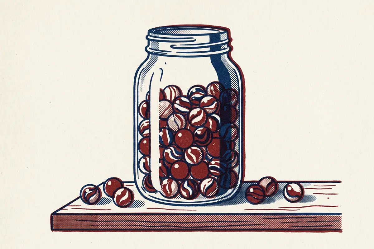 A jar of marbles on a shelf, mostly full, with a few marbles spilled beside it.