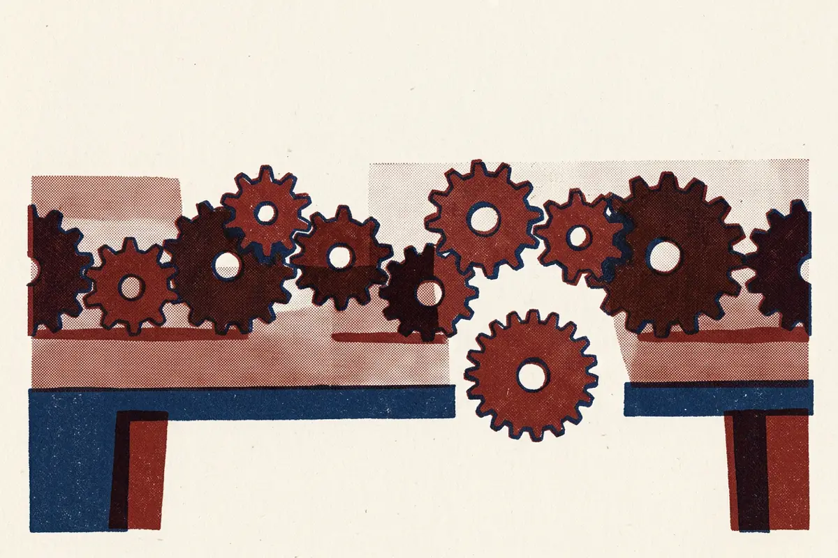A row of interlocking cogs on a table, with one cog standing apart and not connected.