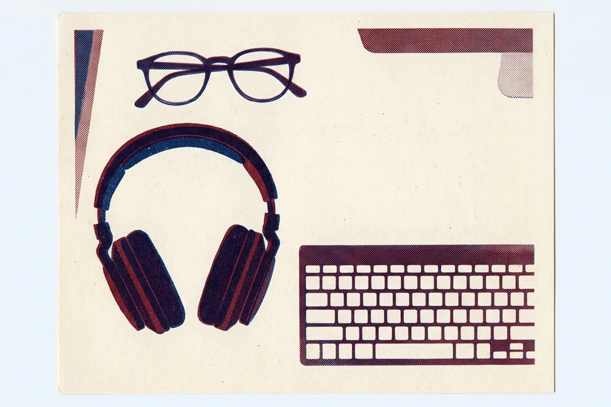 Spectacles, headphones and a keyboard arranged on a desk, seen from above.